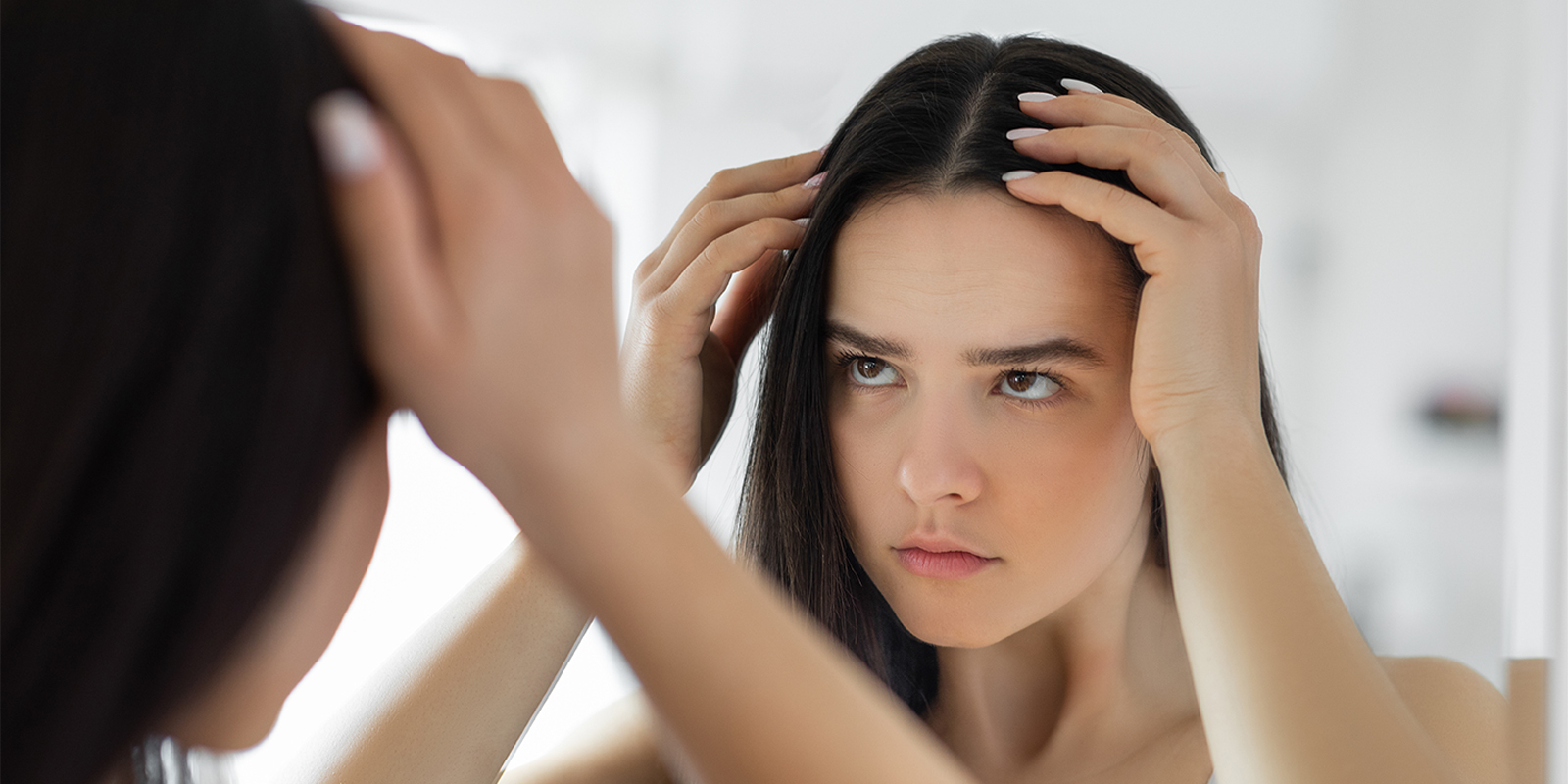 woman looking at her hair in the mirror